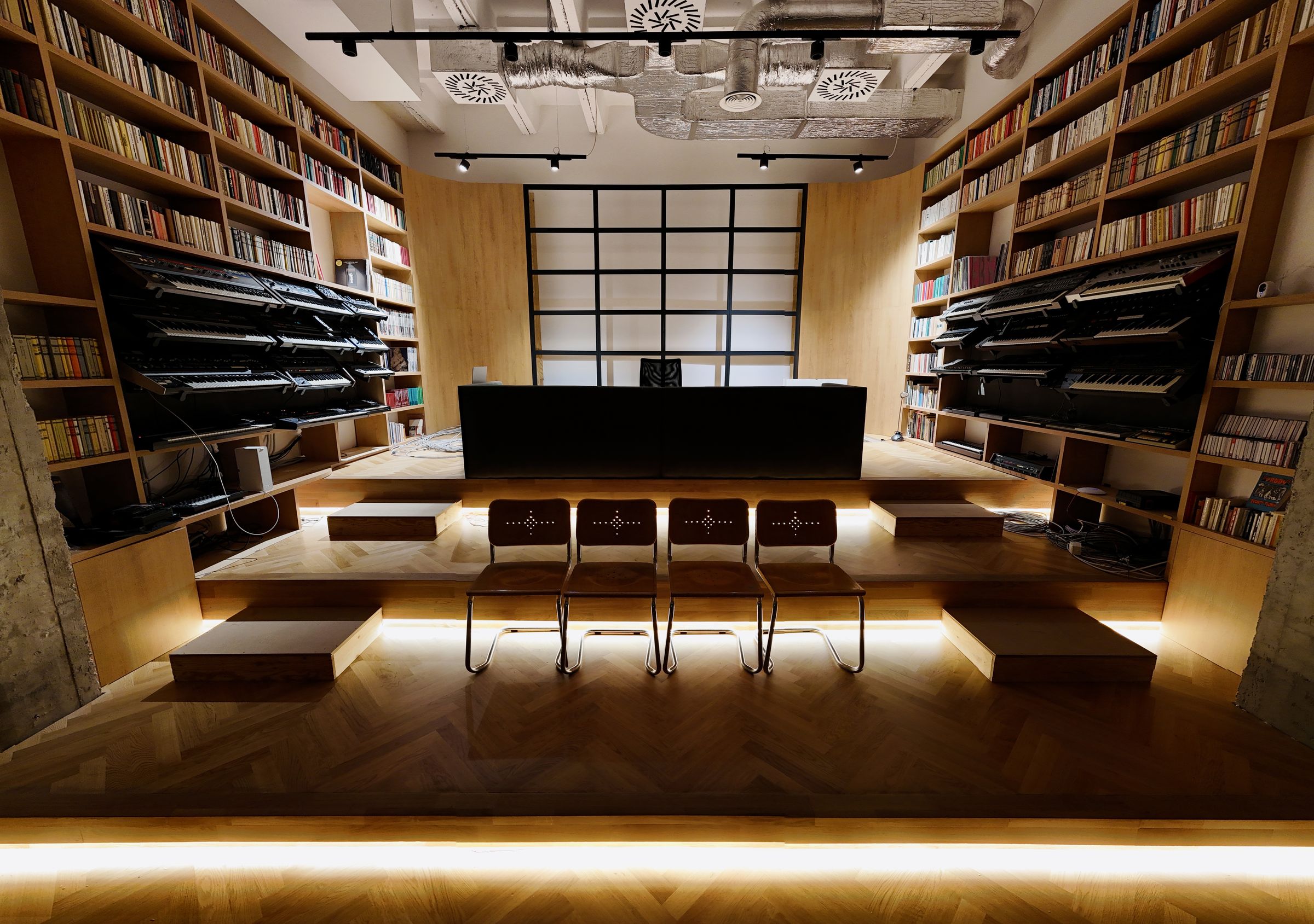 Wide view of the studio interior — stage with chairs between bookshelves.
